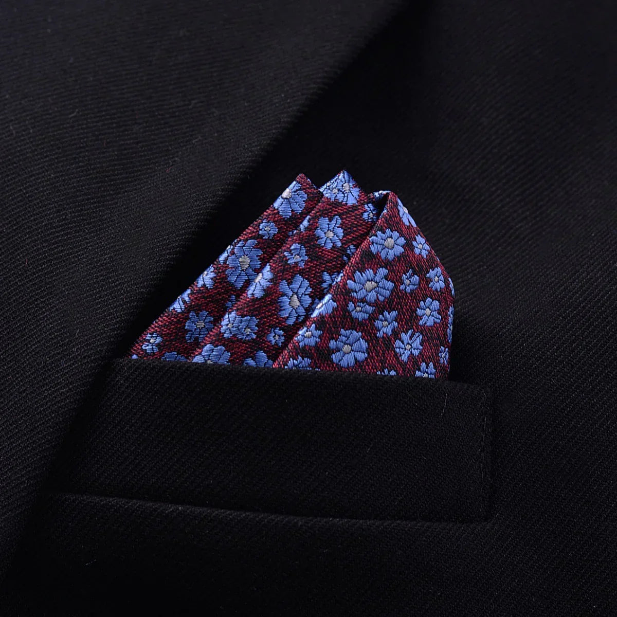 Black suit jacket with a burgundy pocket square featuring blue floral pattern