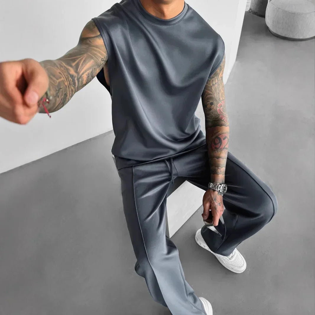 Man wearing sleek gray sleeveless top and matching wide-leg pants, modern streetwear style