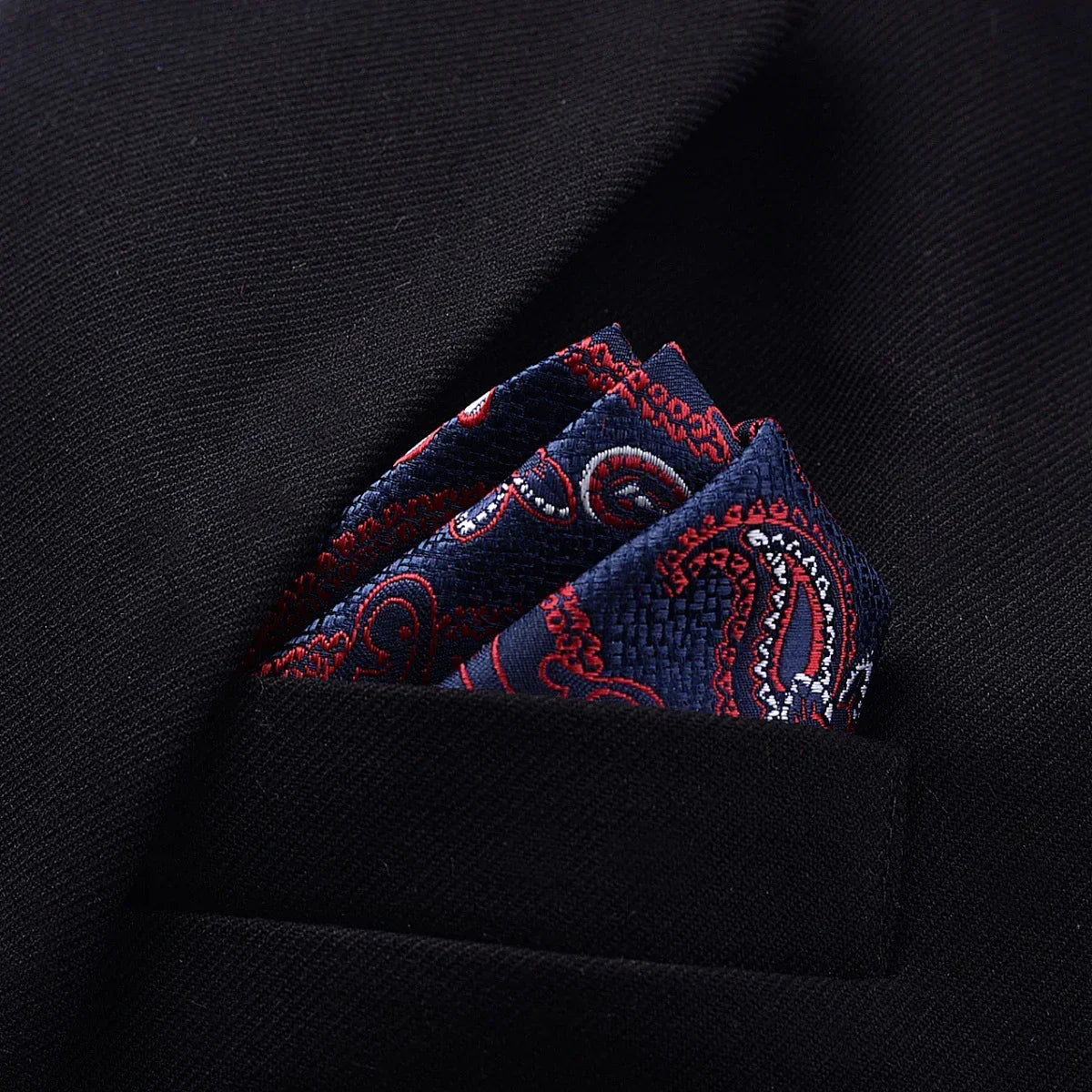 Navy blue silk paisley pocket square with red and white accents in a black blazer