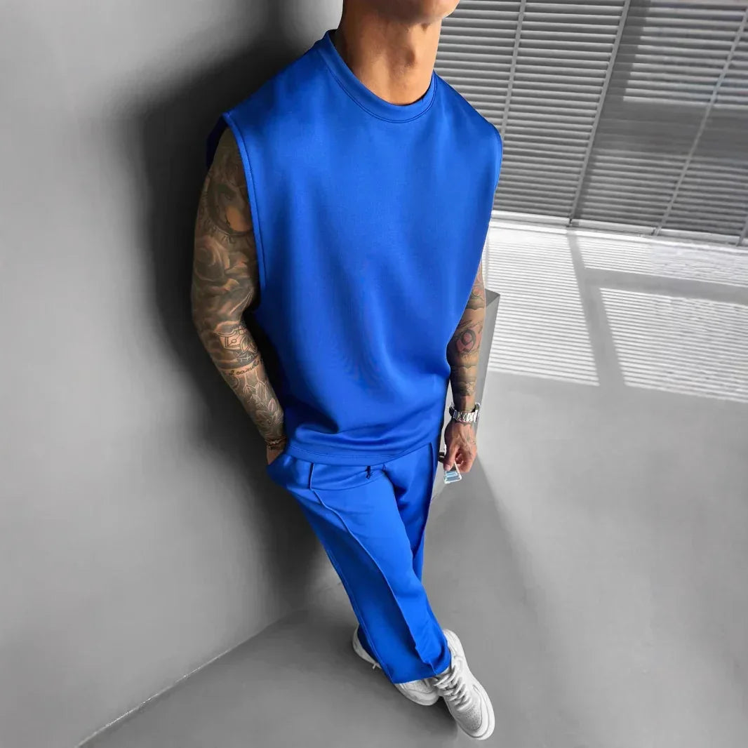 Man wearing a blue sleeveless crewneck top and matching blue jogger pants in relaxed fit