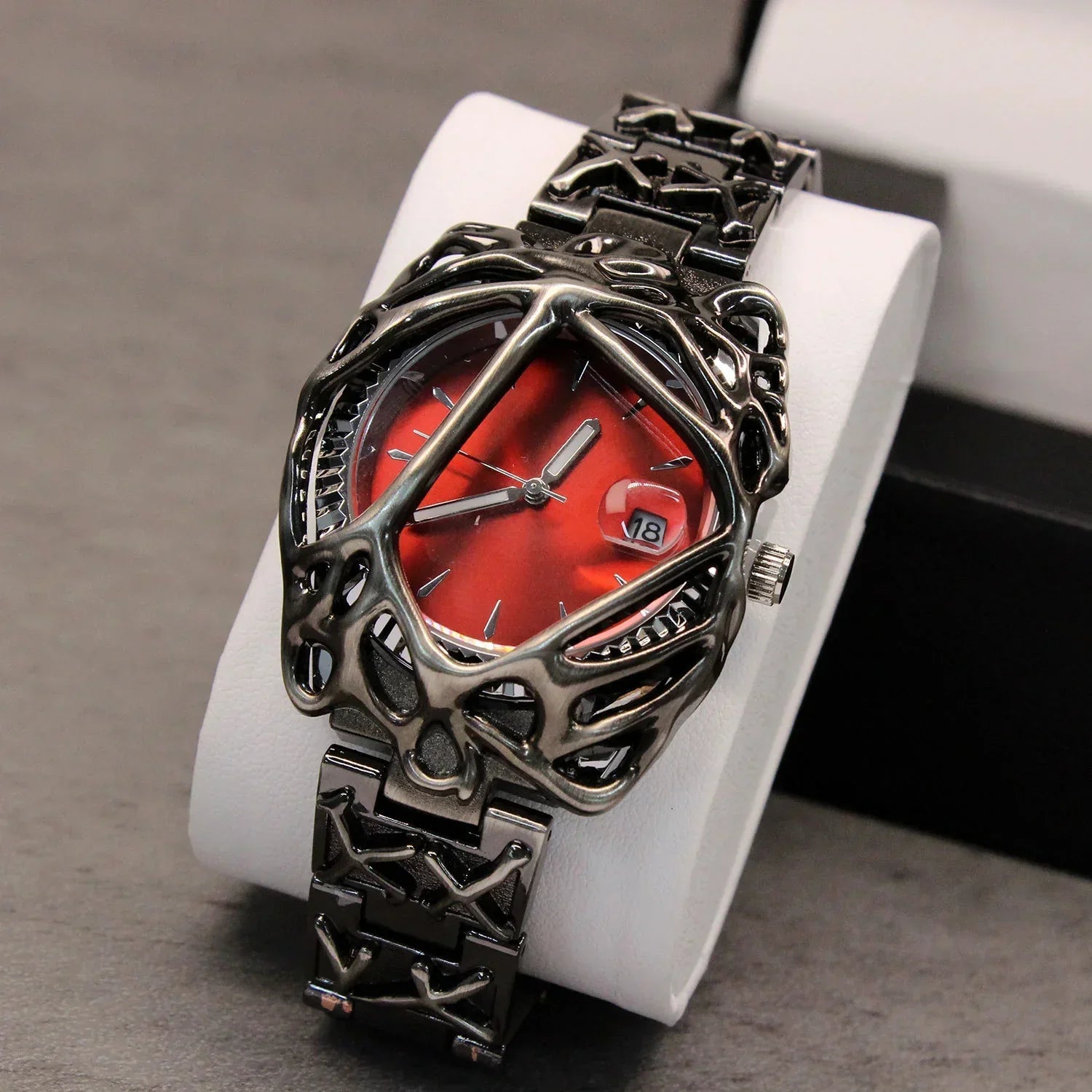 Futuristic metallic wristwatch with a red dial, skeletonized case, and chunky link band.