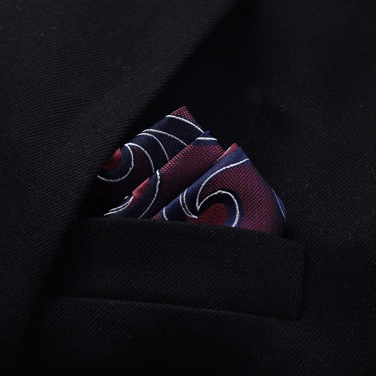 Dark blazer pocket with red and navy patterned silk pocket square, elegant fitted style