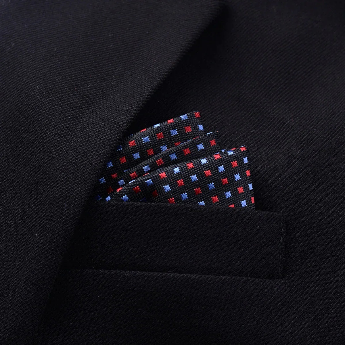 Black suit jacket with a colorful dotted pocket square, close-up on textured fabric.