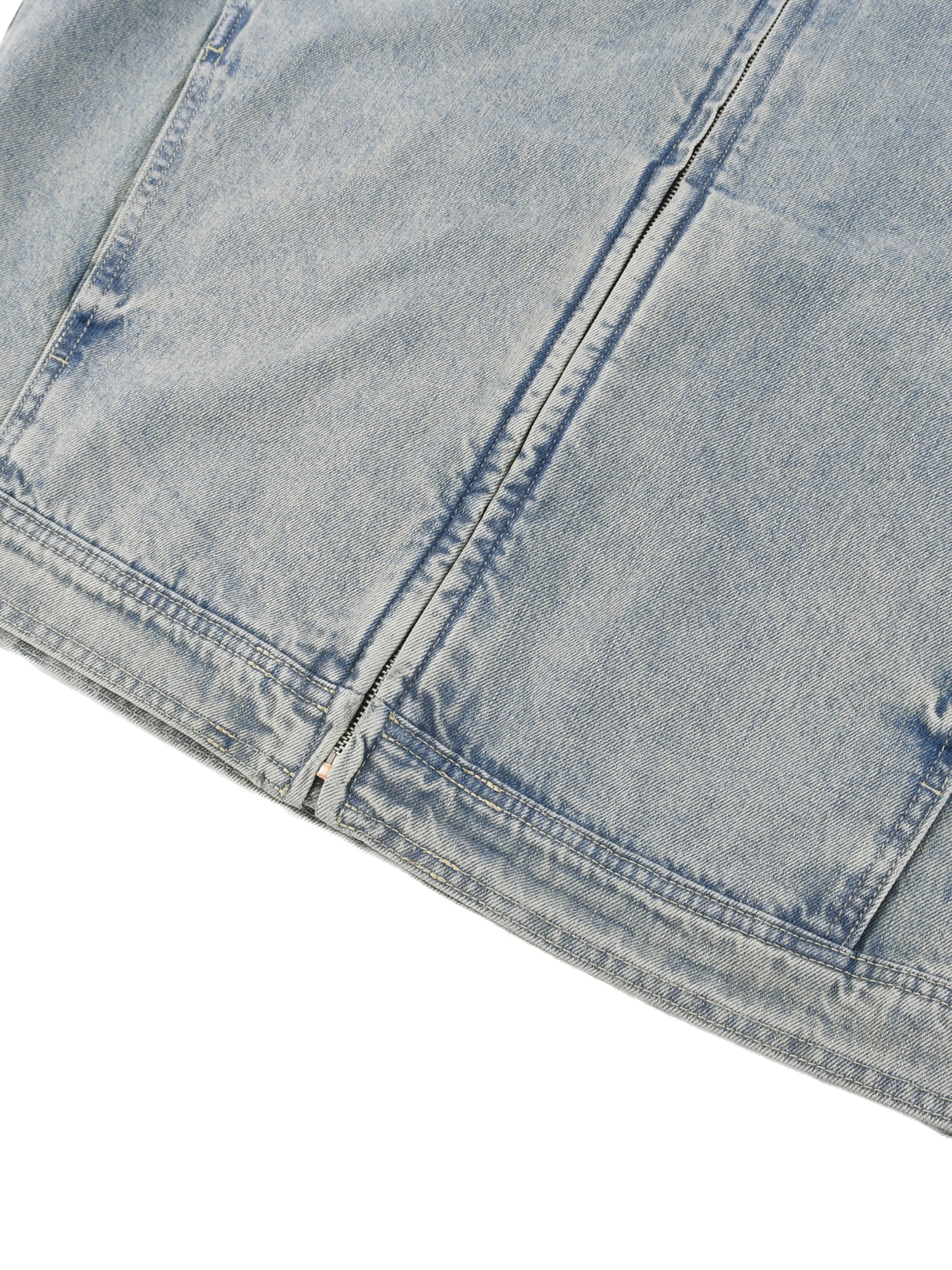 Close-up of a light blue denim fabric with visible stitching on a white background