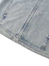 Close-up of a light blue denim fabric with visible stitching on a white background