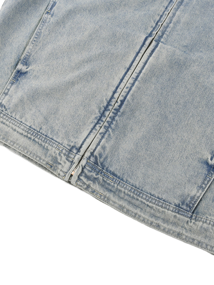Close-up of a light blue denim fabric with visible stitching on a white background