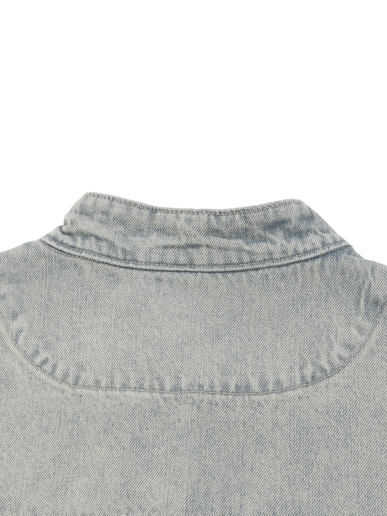 Close-up of a light blue denim shirt collar on a white background
