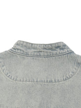 Close-up of a light blue denim shirt collar on a white background