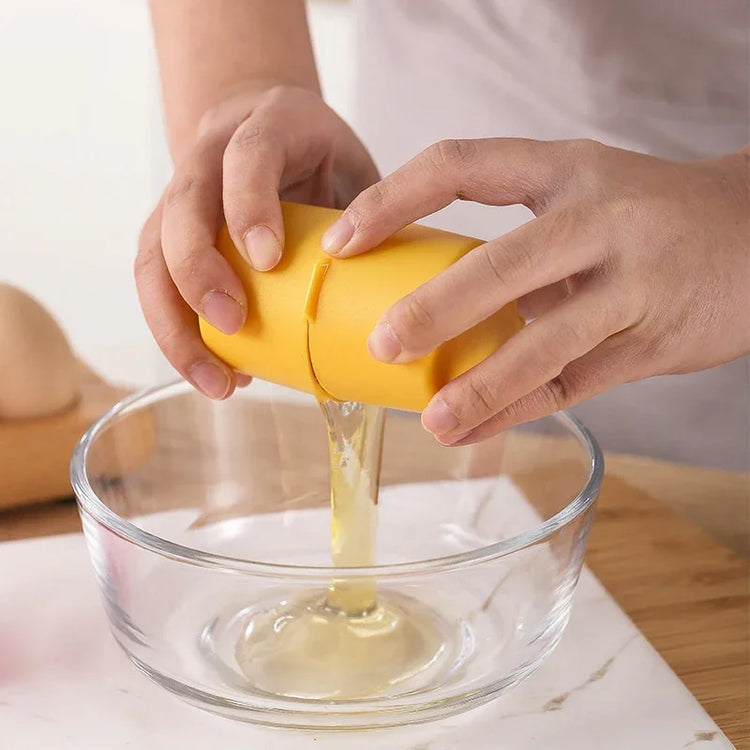 Hands using a yellow kitchen tool to crack an egg into a glass bowl on a countertop.