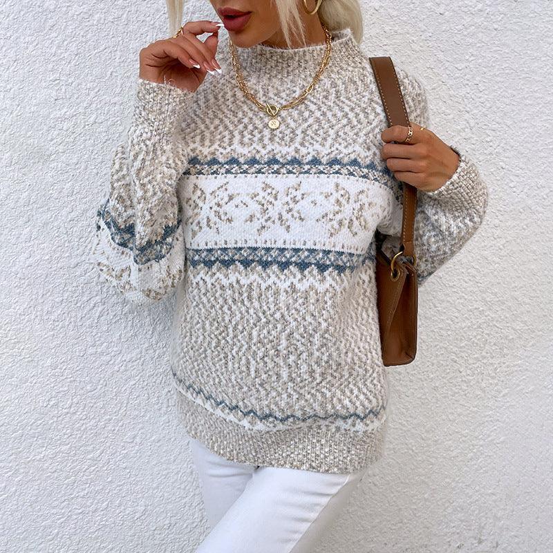 Woman wearing a beige and white knit sweater with blue geometric patterns and relaxed fit.