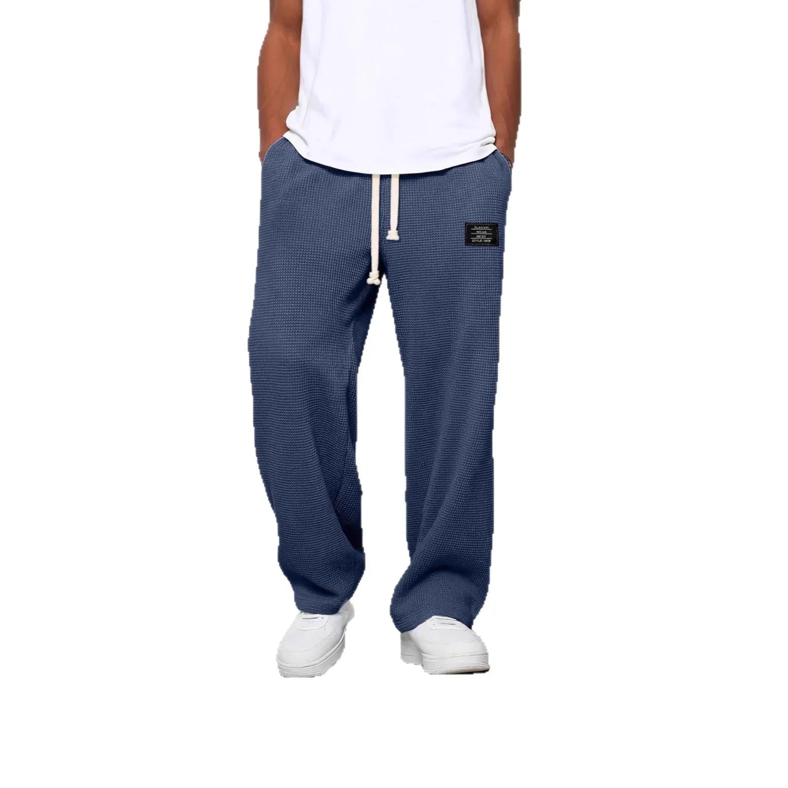 Man wearing relaxed-fit blue textured jogger pants with drawstring waist and patch detail