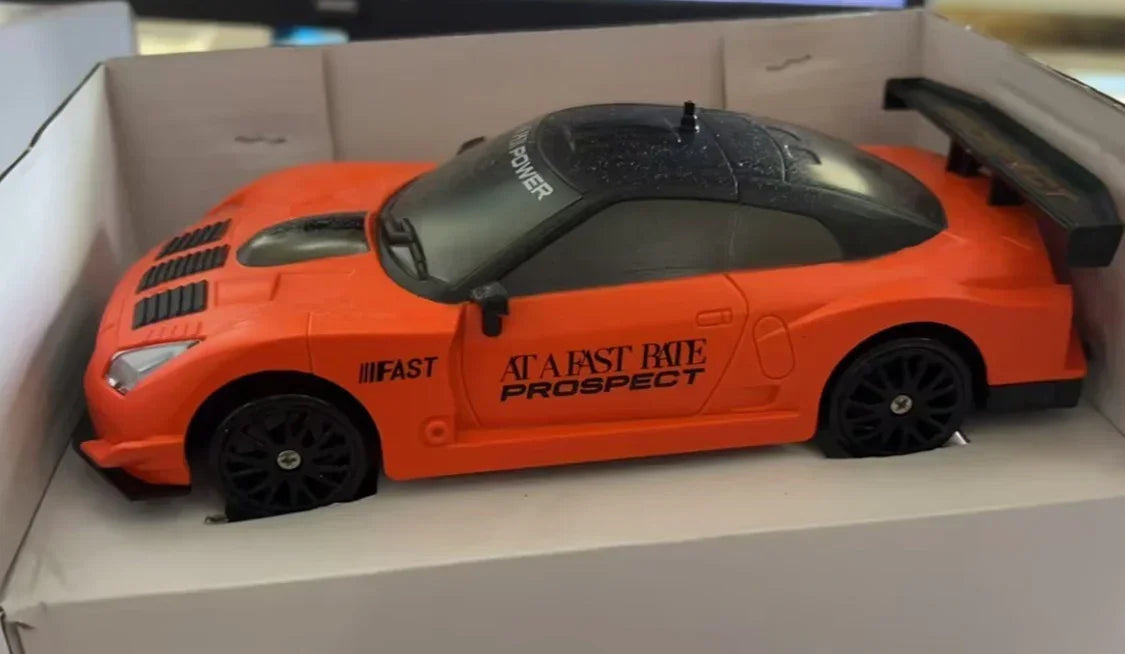 Orange and black toy sports car with racing decals in a white display box