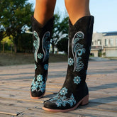 Black suede knee-high boots with blue floral embroidery, chunky heel, western style