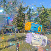Colorful plastic bubble guns with blue, yellow, white, and purple details in a park setting