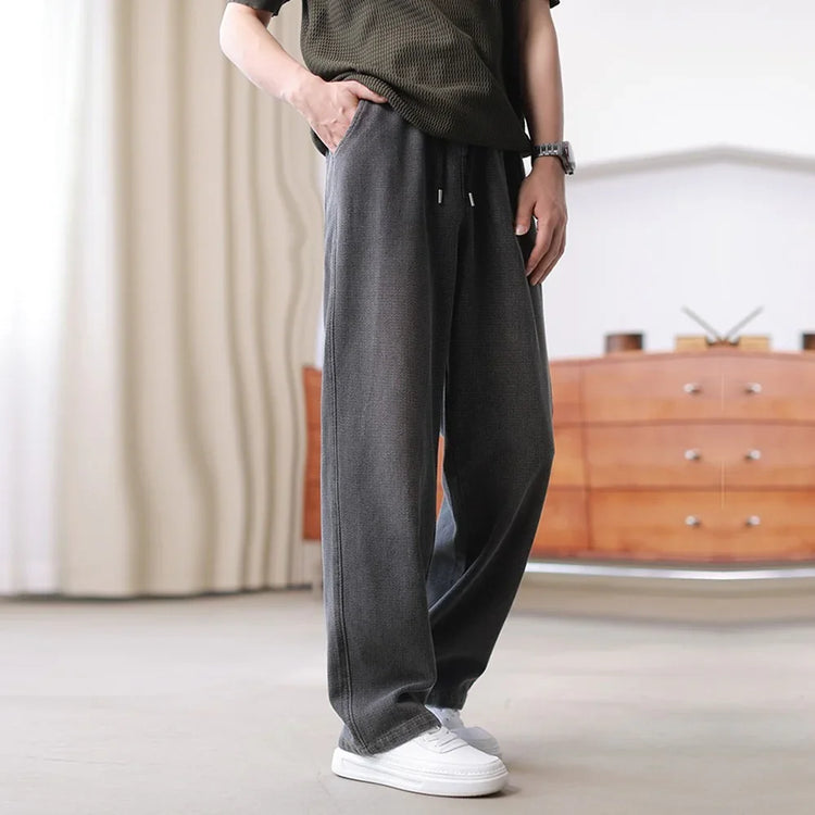 Loose fit gray streetwear pants with drawstring waist, paired with white sneakers