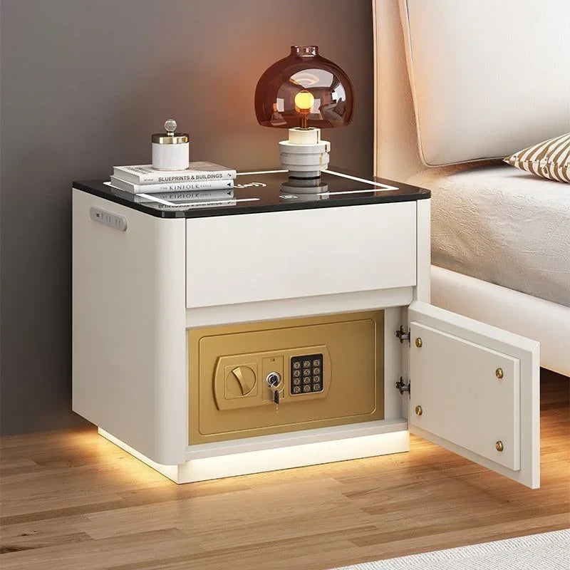 Modern white bedside table with black top, gold safe, LED lighting, and minimal decor