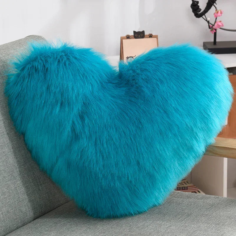Fluffy turquoise heart-shaped faux fur pillow on a modern gray sofa