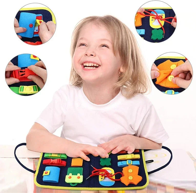 Child wearing a white short-sleeve t-shirt interacting with a colorful felt activity board featuring buttons, buckles, and laces.