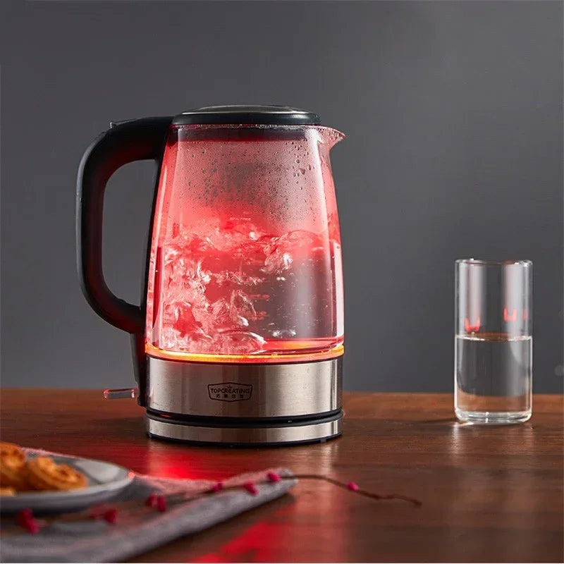 Glass electric kettle with boiling water and red LED light on wooden table