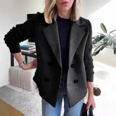 Woman wearing black double-breasted wool blazer with ribbed knit sleeves and relaxed fit.