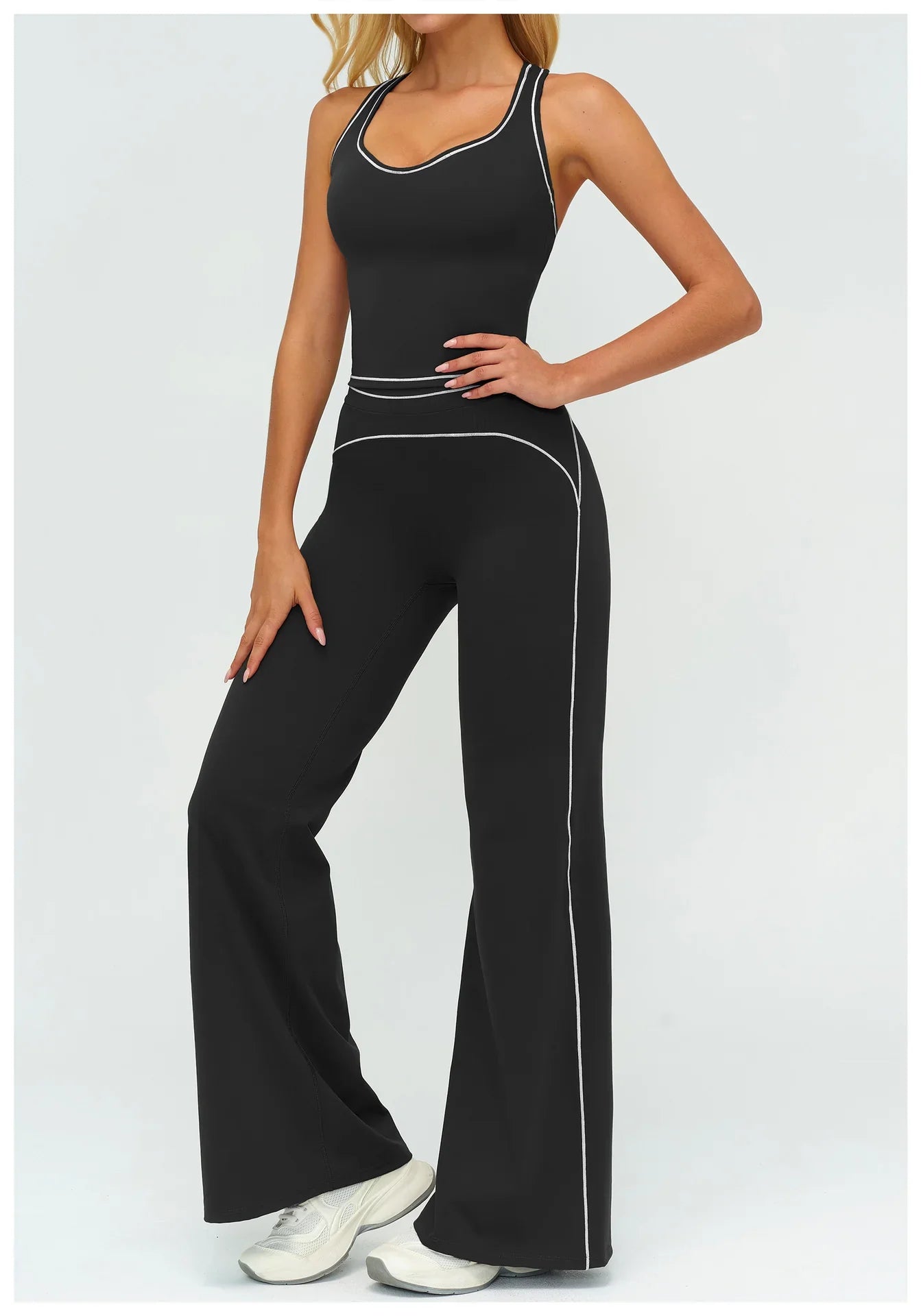 Woman wearing black fitted tank jumpsuit with white contrast stitching and flared legs