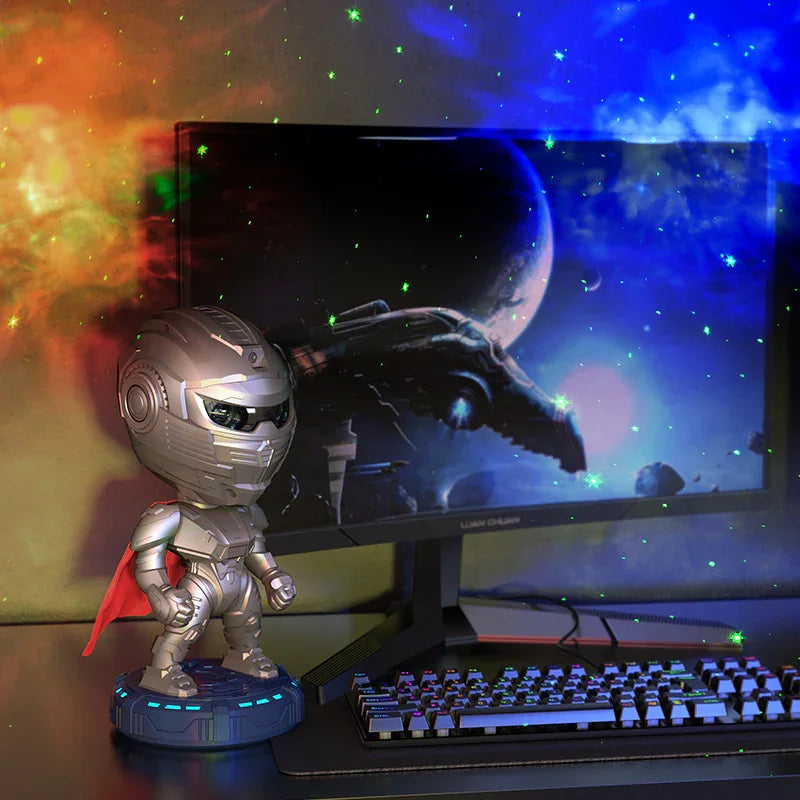Silver armored robot figurine with red cape on gaming desk, beside RGB keyboard and space-themed monitor background.