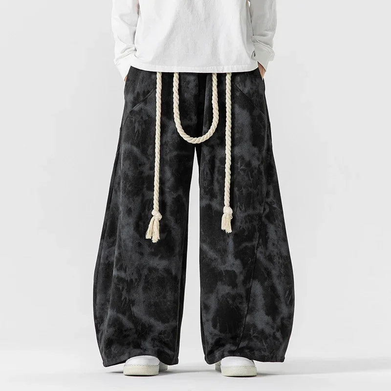 Black tie-dye wide-leg pants with rope belt, loose fit streetwear style.