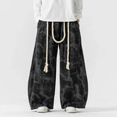 Black tie-dye wide-leg pants with rope belt, loose fit streetwear style.