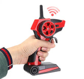 Hand holding a black and red remote control with ergonomic grip and wheel for RC car.