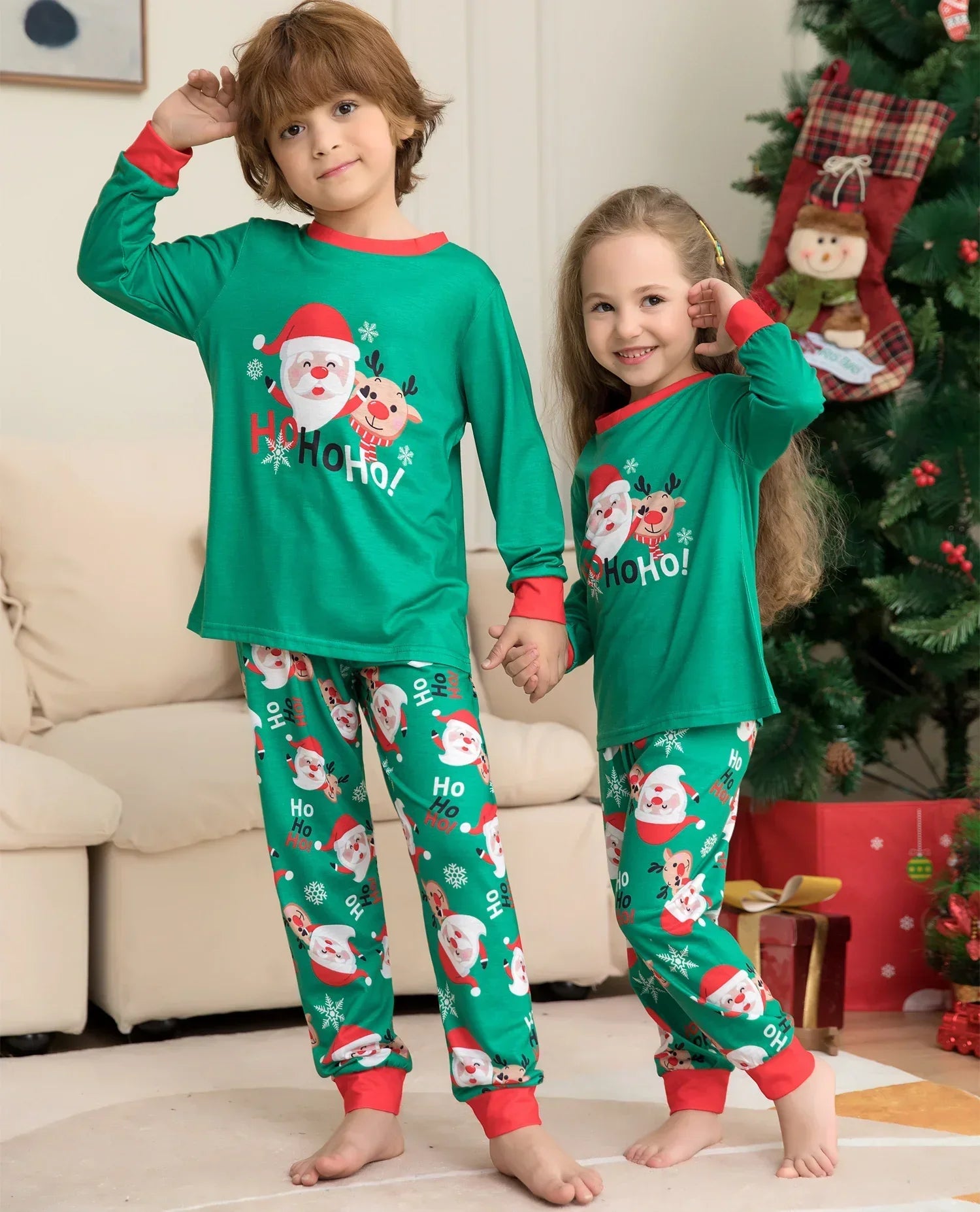 Kids wearing matching green Christmas pajamas with Santa Claus print, red cuffs, relaxed fit