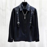 Black long sleeve shirt with metal buckle straps, grommet details, and silver chain necklace, modern streetwear style.