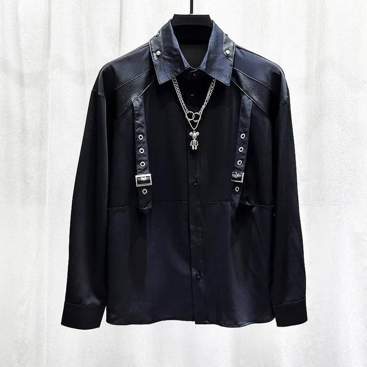 Black long sleeve shirt with metal buckle straps, grommet details, and silver chain necklace, modern streetwear style.