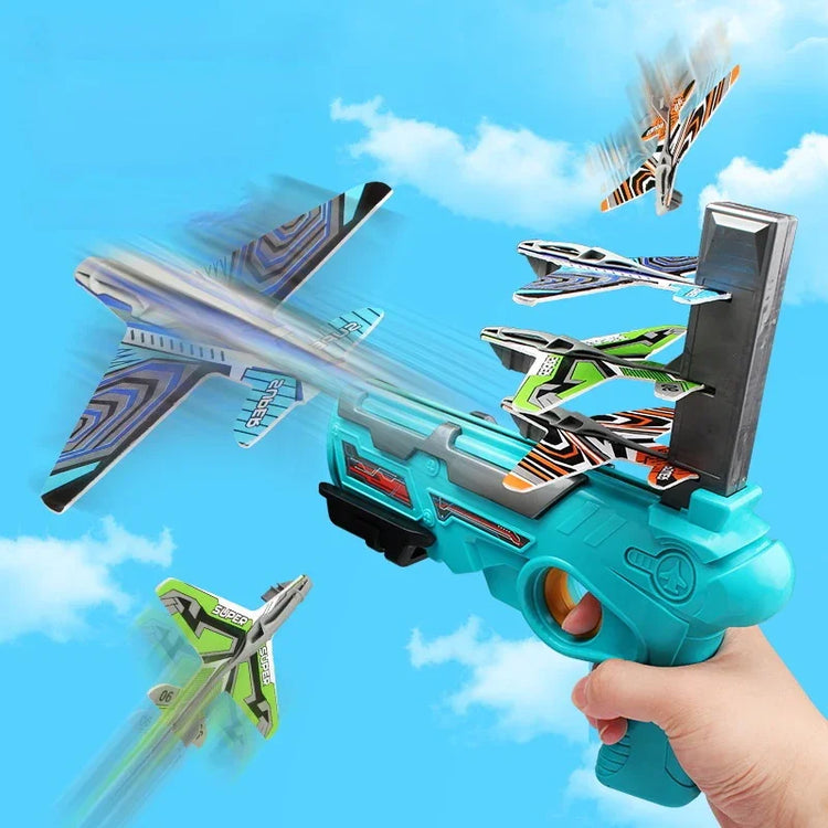 Hand holding a blue foam plane launcher toy with colorful glider planes flying in the sky