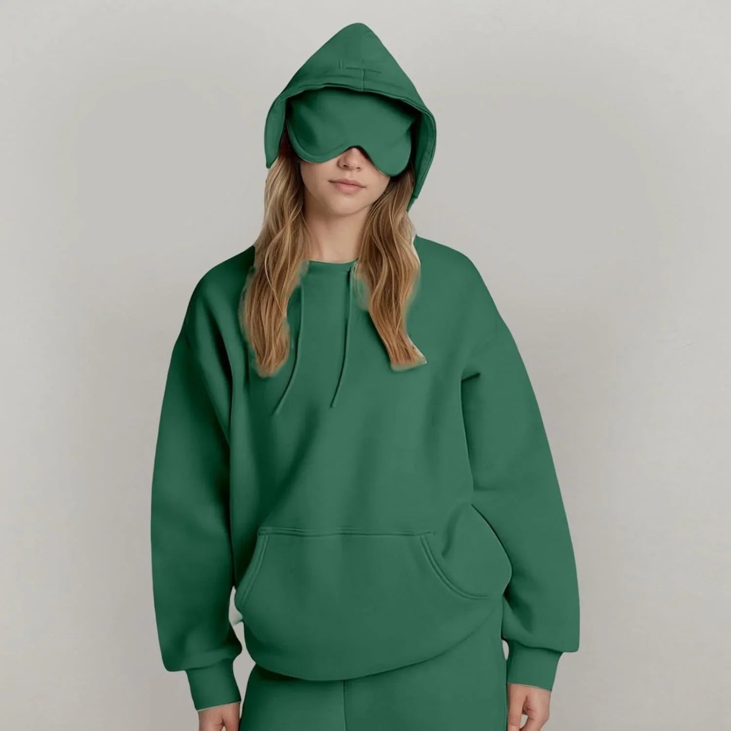 Woman in oversized green hoodie and matching sweatpants with attached eye mask, relaxed fit