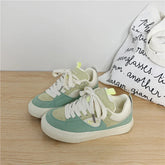 Pastel green and beige suede low-top sneakers with white laces and chunky sole, casual style.
