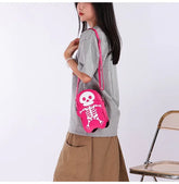Woman wearing oversized gray t-shirt, khaki wide-leg pants, and carrying pink skeleton crossbody bag