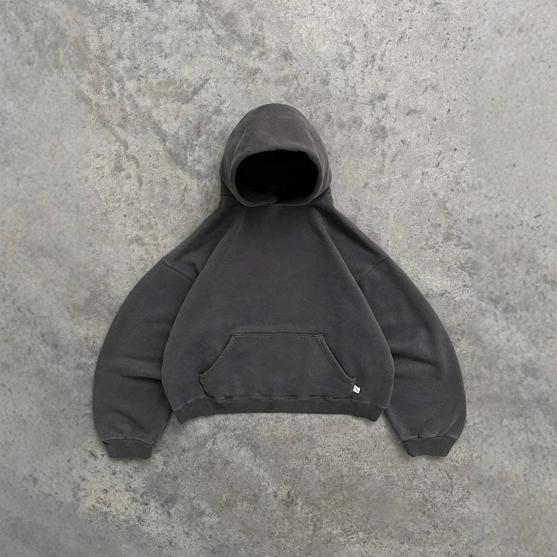 Oversized dark grey hoodie with kangaroo pocket and relaxed fit on concrete background