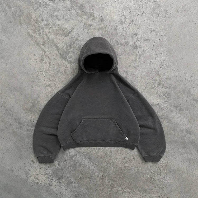 Oversized dark grey hoodie with kangaroo pocket and relaxed fit on concrete background