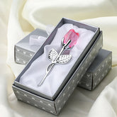Silver metal rose with pink crystal bloom in a gift box on white fabric