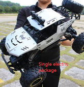 Person holding a large white off-road remote control car with rugged tires outdoors.