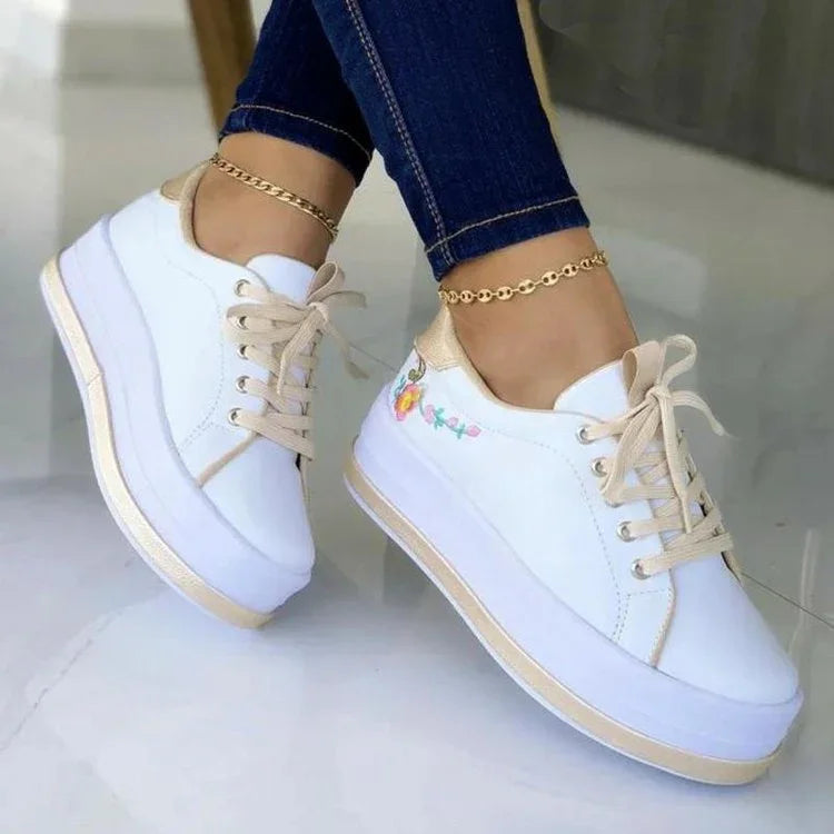 White platform sneakers with beige accents, floral embroidery, casual fit, worn with skinny jeans