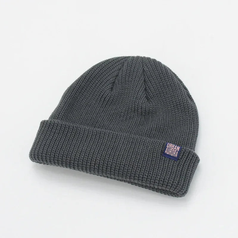 Dark gray waffle knit beanie with folded cuff and small patch label, streetwear style