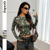 Woman wearing fitted long sleeve green camouflage print top with high-waisted dark jeans