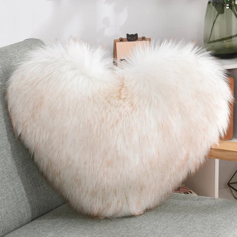 Heart-shaped faux fur pillow in white and pale pink on a modern sofa
