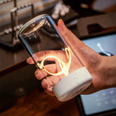 Hand holding modern glass LED lamp with spiral filament and white base indoors