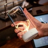 Hand holding modern glass LED lamp with spiral filament and white base indoors