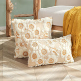 Two rectangular cream and yellow floral throw pillows with textured fabric on wooden floor