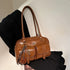 Brown faux leather shoulder bag with front pockets and keychain, modern streetwear style
