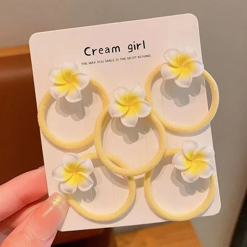 Set of five pastel yellow elastic hair ties with white and yellow flower accents, soft material