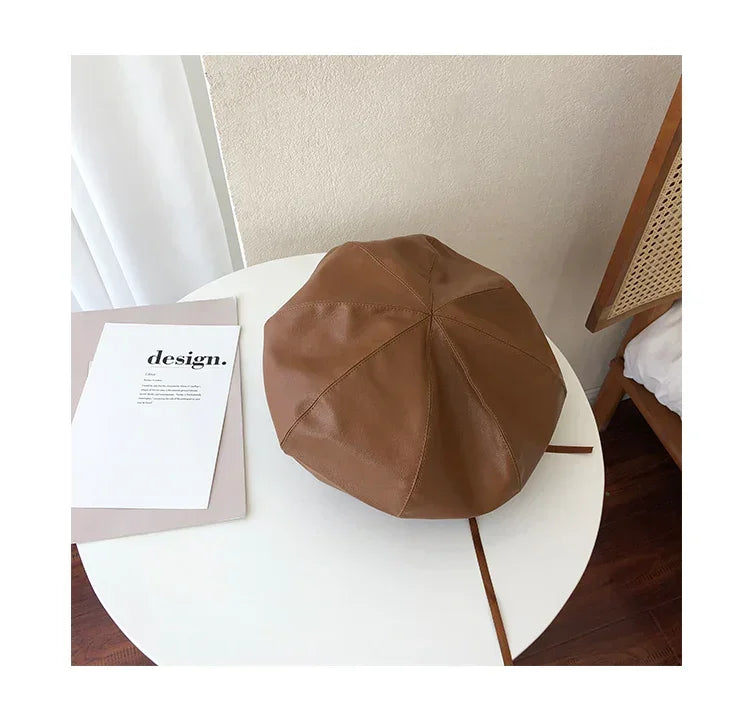 Brown faux leather beret with stitched panels, minimalist modern style, on white table